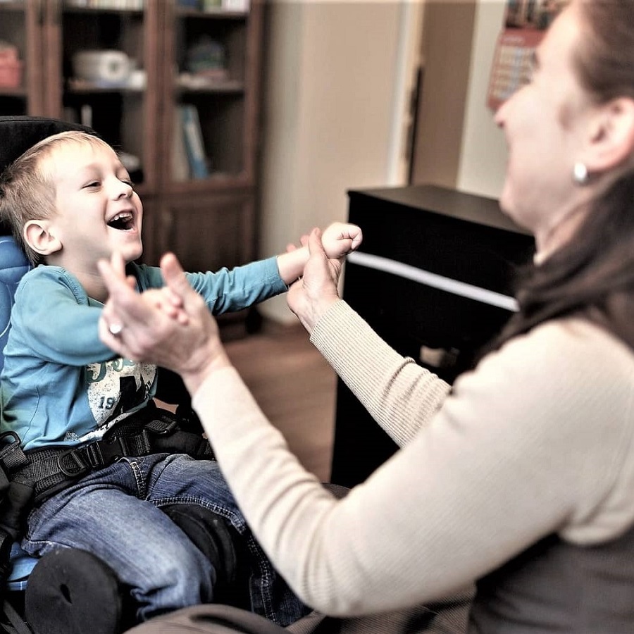 Женщина держит за руки ребенка инвалида